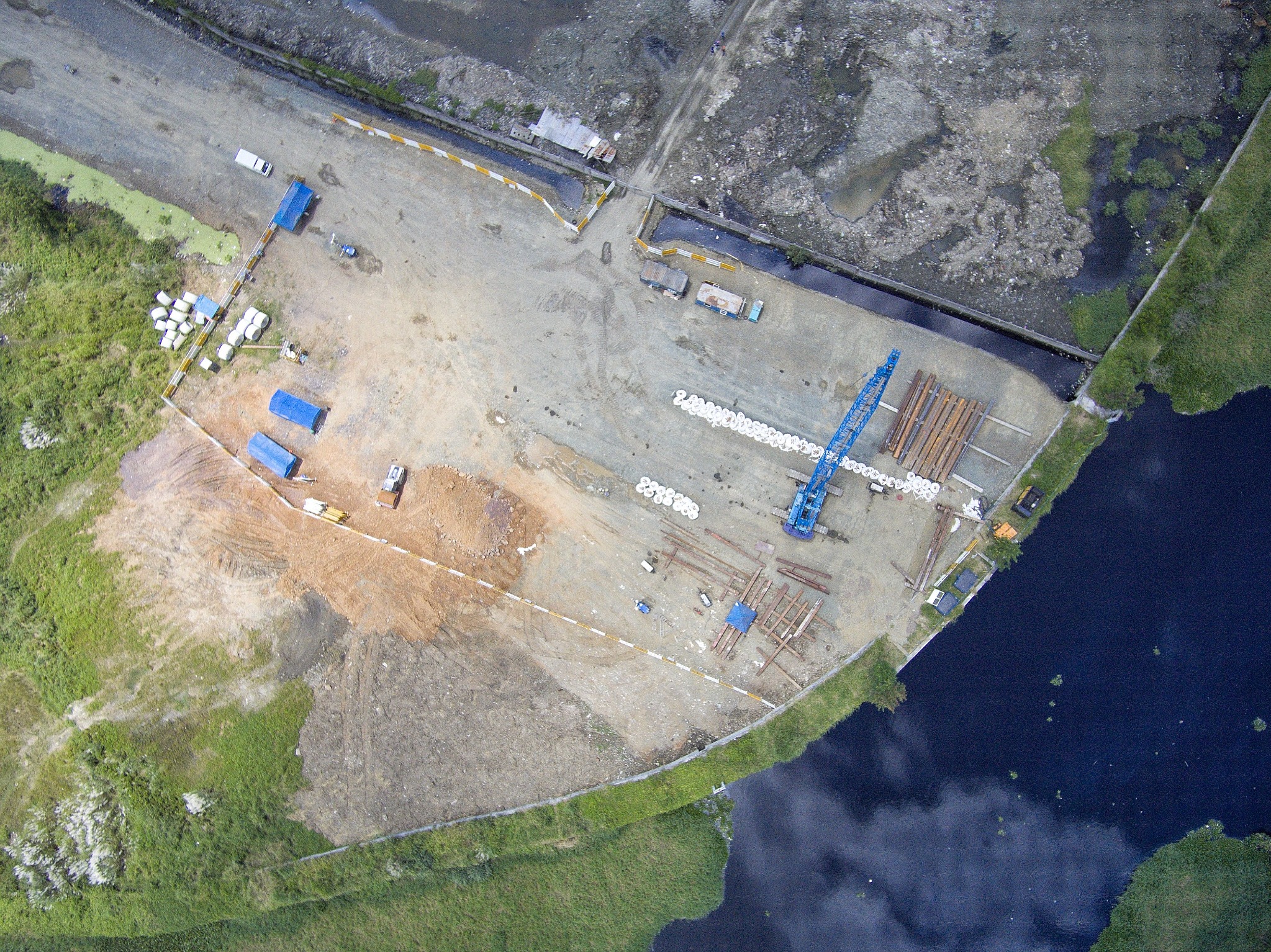 Overhead drone photograph of an industrial site beside water